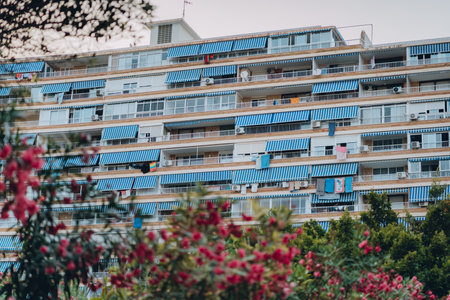 A facade of a building in Alicante, Spain with repeating blue striped awnings over numerous balconies, reflecting organized urban architecture.の写真素材