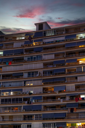 A multi-story residential building in Alicante, Spain illuminated at dusk, showing a blend of natural and artificial light.の写真素材