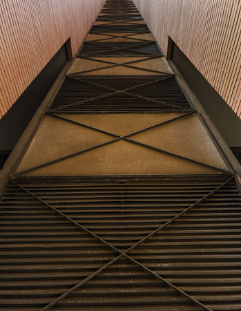 A striking upward view of a modern architectural corridor featuring repeating geometric patterns,...