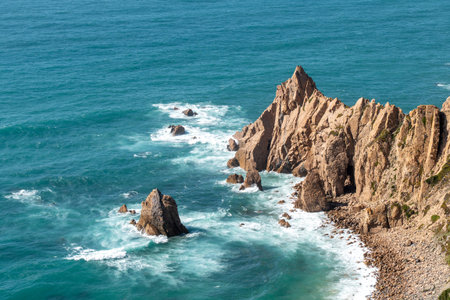 Stunning jagged cliffs meet the vibrant turquoise Atlantic Ocean near Lisbon, Portugal, perfect for...