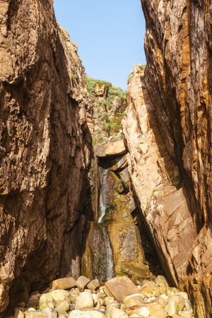 A striking natural scene featuring a small waterfall cascading between rugged cliffs in the Lisbon area, ideal for travel, adventure, and geology-related visual content.の写真素材