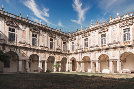 Elegant courtyard of an old Lisbon monastery featuring arched walkways, weathered stone, and...