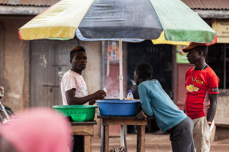 KIBALE NATIONAL PARK, UGANDA - MARCH 15, 2018: An unidentified local men chat at the roadside market on March 15, 2018 in the village near Kibale National Park, Ugandaのeditorial素材