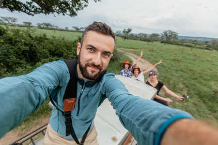 QUEEN ELIZABETH NATIONAL PARK, UGANDA - MARCH 14, 2018: An unidentified man takes a selfie from the roof of the safari jeep on March 14, 2018 in Queen Elizabeth National Park, Ugandaのeditorial素材