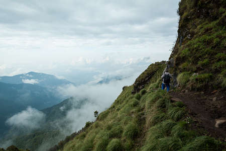 NEPAL - MAY 31, 2016: An unidentified man walks on the narrow trail on the edge of the mountain on the trekking route to Machapuchare on May 31, 2016 in Nepalのeditorial素材