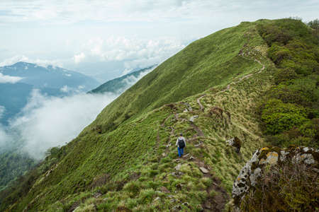 NEPAL - MAY 31, 2016: An unidentified man walks on the narrow footpath on the green-capped mountain ridge on the trekking route to Machapuchare on May 31, 2016 in Nepalのeditorial素材