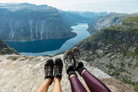 Mans and womans feet in shoes on the background of mountains, Trolltunga, Vestland county, Norwayの写真素材