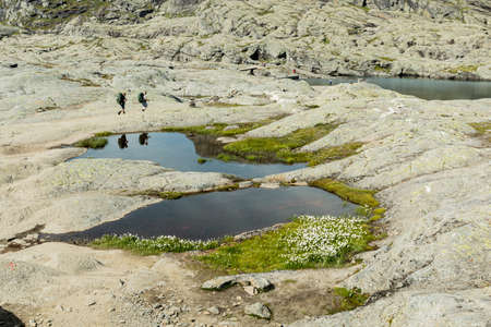 VESTLAND COUNTY, NORWAY - JULY 26, 2019: Two hikers walk on the rock formation on the hiking route to Trolltunga, Vestland county, Norwayのeditorial素材