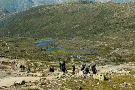 VESTLAND COUNTY, NORWAY - JULY 26, 2019: A group of hikers walks on the hiking trail to Trolltungaのeditorial素材