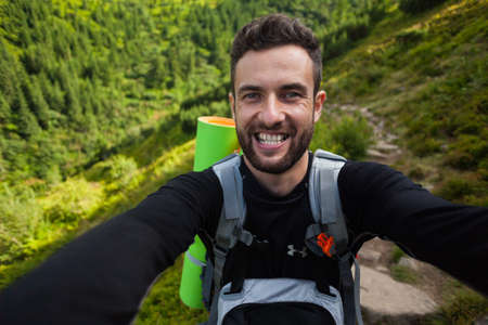 Young and happy man takes a selfie in Carpathian mountains, Ukraineの写真素材
