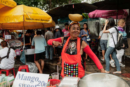 BANGKOK, THAILAND - MAY 3, 2014: Street vendor lady with a large mango on her headのeditorial素材