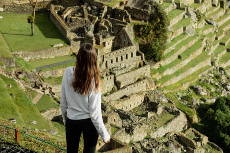 A young woman looks at the ruins of Machu Pichhuの写真素材