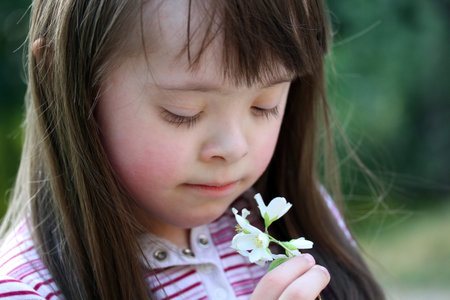 Portrait of beautiful young girl with flowers in the parkの写真素材