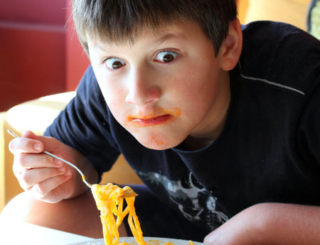 Funny boy eating spaghetti.の写真素材