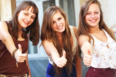 Beautiful student girls smiling and giving thumbs upの写真素材