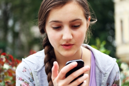 Girl with a mobile phone reads the messageの写真素材