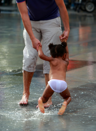 PARIS, FRANCE - SEP 07: Little girl playing with father in a puddle of Republic Square on weekend on sep 07. 2014 in Paris, France.のeditorial素材