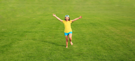 Young girl run on the background of green grassの写真素材