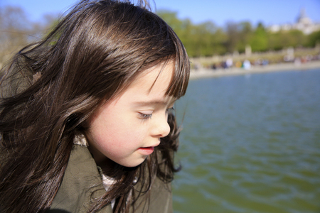 Portrait of little girl looking on the water in the parkの写真素材