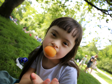 Young girl eating apricot in the parkの写真素材