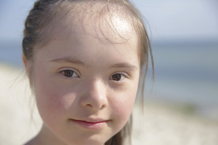 Portrait of down syndrome girl smiling on background of the seaの写真素材