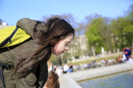 Portrait of little girl looking on the water in the parkの写真素材