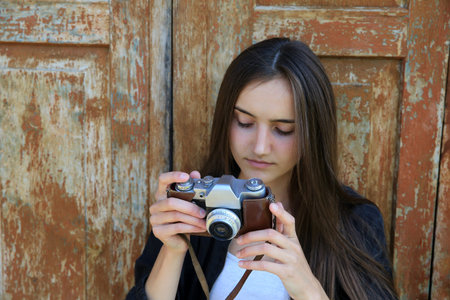 Beautiful girl with a camera on vintage wooden door background.