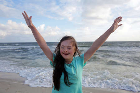 Portrait of down syndrome girl smiling on background of the seaの写真素材