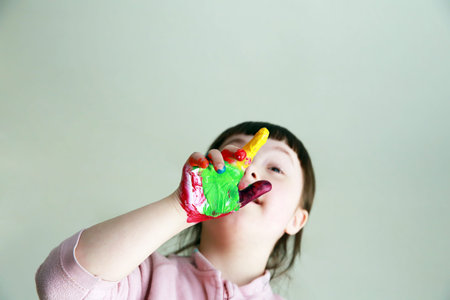 Cute little girl with painted hands. Isolated on gray background.の写真素材