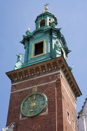 Close-up view of a historic brick clock tower with a large green clock face and copper roof in...