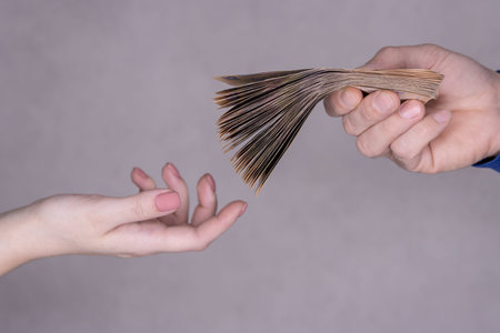 hands giving money isolated on gray background.Finance concept.Male hands give stack of money to...