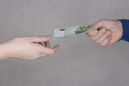 hands giving money 100 euro isolated on gray background close-up.の写真素材