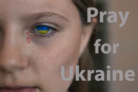 sad face of a child with the eyes of the flag of Ukraine and a tearの写真素材