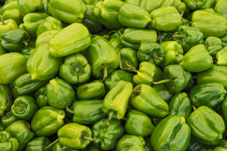 a lot of green peppers in the market on the counter, the backgroundの写真素材