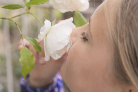 A teenager stands sniffing white flowers on a tree.Flowers in focus close-upの写真素材