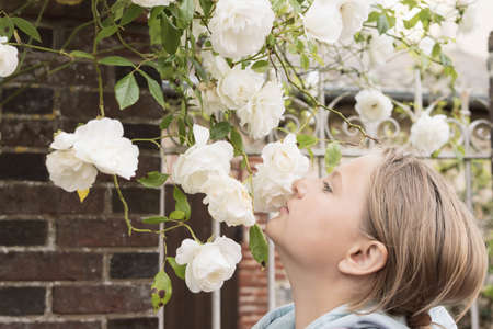 A teenager stands sniffing white flowers on a tree.Flowers in focusの写真素材