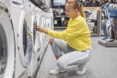 a girl of fair appearance with blond hair tied in a ponytail in a yellow sweater in jeans and light...