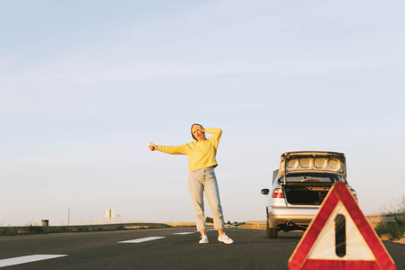 in the foreground, a red-white emergency stop sign, a girl in a yellow sweater and jeans stands with...