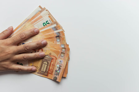 a mans hand close-up on a white background holds a hand spread out euros for 50. with the right...