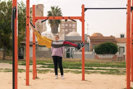 A boy and a girl are teenagers on the playground in the park go in for sports. The boy pulls himself...