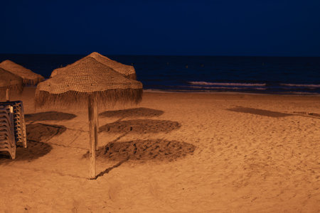 photo of a beautiful evening beach without people, clean evening beach, there is a place for an inscription close-up on sun umbrellas on the beachの写真素材