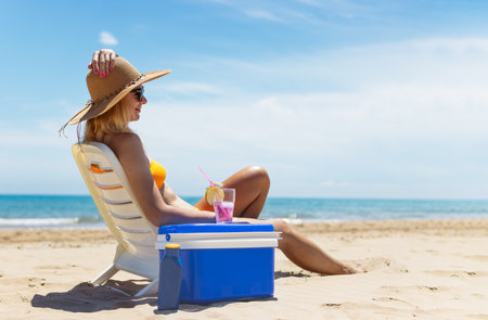 Happy young european girl drinks a cocktail and rests in a sun lounger on the beach,の写真素材