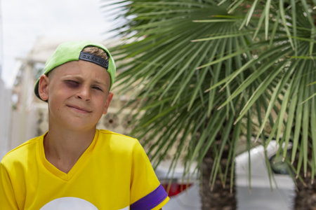 a boy with a black eye sits in the park, portrait of a boy in a cap with a black eyeの写真素材