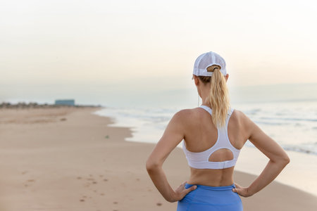 a girl in blue tights and a white top stands against the backdrop of the sea at dawn doing exercises