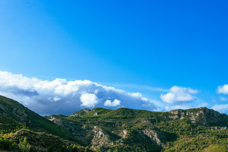 Photograph of a mountain landscape, view of a mountain with forest and clouds.の写真素材