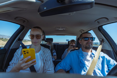 Family members riding in a car, engrossed in their smartphones and digital devices, representing a modern problem of screen addiction and disconnection during travel