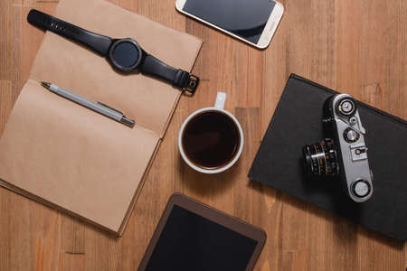 wooden desk phone notebook photo camera clock tablet coffe bookの写真素材