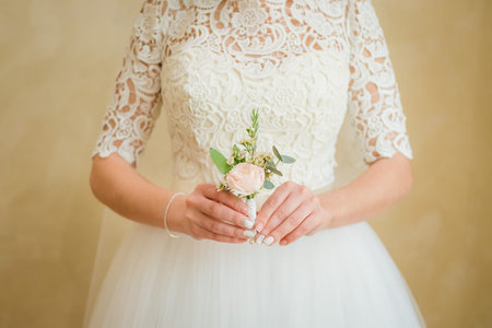 boutonniere groom in the hands of the bride. Gentle hand of the bride boutonniere for the groom....