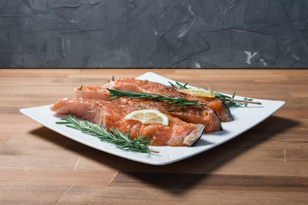 fresh raw red fish fillet on white plate and rosemaryの写真素材