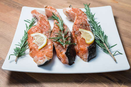 fresh raw red fish fillet on white plate and rosemaryの写真素材